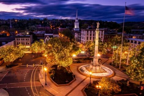 A nighttime view of the Center Circle of Downtown Easton, featuring the fountain and monument surrounded by lit lanterns and trees covered in lights.