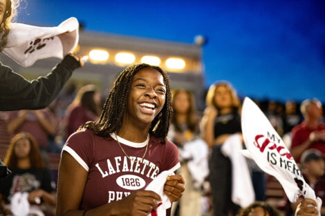 A student wearing Lafayette College gear cheers from the stands.