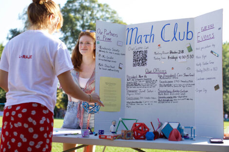 A student stands next to a poster about Math Club.