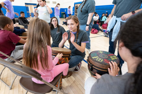 A Lafayette student teaches an elementary aged student drums.