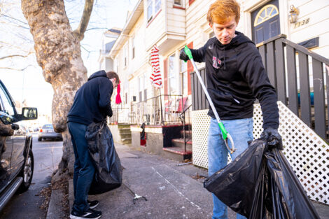 A student picks up trash and puts it into a trash bag during a city clean up event.