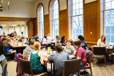 Students sit at long tables with food.