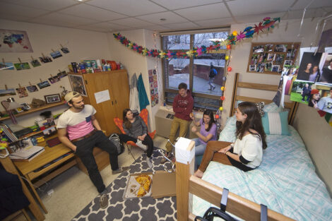 Students stand around a residence hall.